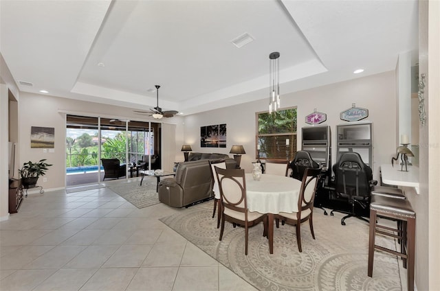 dining area featuring ceiling fan, light tile patterned flooring, and a raised ceiling