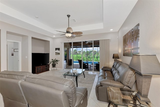 living room featuring ceiling fan, light tile patterned floors, and a tray ceiling