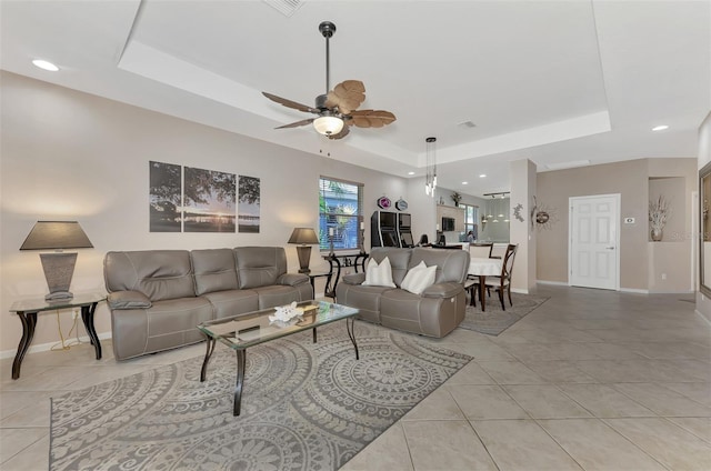 living room featuring ceiling fan, light tile patterned floors, and a tray ceiling