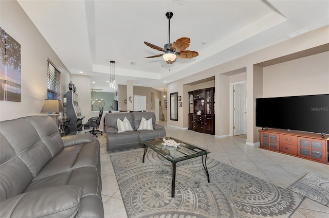 tiled living room featuring a raised ceiling and ceiling fan