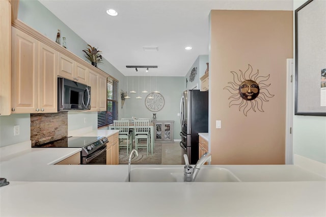 kitchen featuring stainless steel appliances, rail lighting, backsplash, sink, and kitchen peninsula