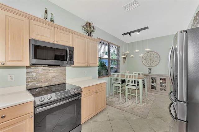 kitchen with tasteful backsplash, hanging light fixtures, track lighting, stainless steel appliances, and light tile patterned floors