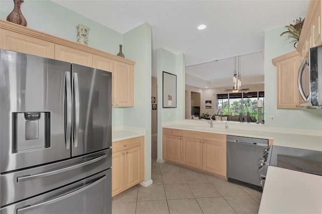 kitchen with light tile patterned floors, appliances with stainless steel finishes, light brown cabinets, hanging light fixtures, and sink