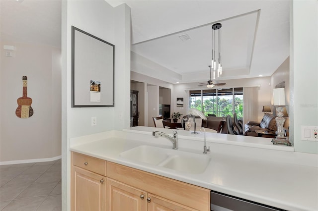 kitchen featuring a raised ceiling, light tile patterned flooring, light brown cabinetry, dishwasher, and sink