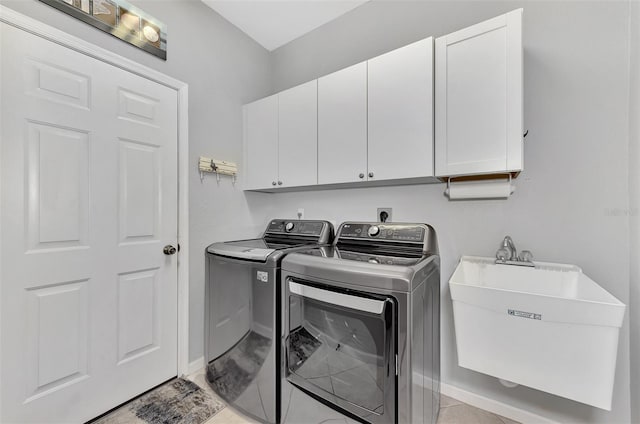 washroom with light tile patterned flooring, cabinets, washer and dryer, and sink