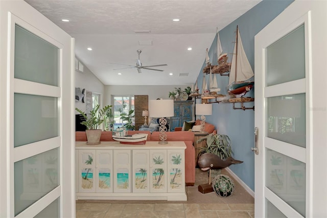 living room featuring ceiling fan, a textured ceiling, and lofted ceiling