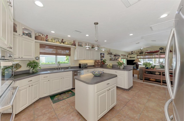 kitchen with vaulted ceiling, a kitchen island, sink, stainless steel appliances, and white cabinets