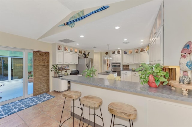 kitchen with lofted ceiling, white cabinets, stainless steel refrigerator with ice dispenser, and kitchen peninsula