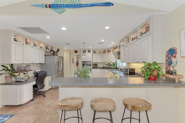 kitchen featuring kitchen peninsula, sink, white cabinetry, a breakfast bar area, and double oven