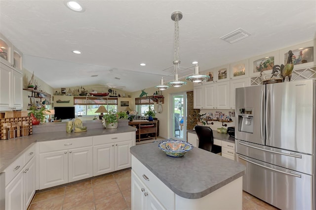 kitchen featuring vaulted ceiling, a center island, white cabinetry, hanging light fixtures, and stainless steel fridge