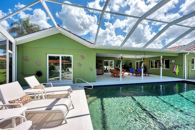 view of pool featuring ceiling fan, glass enclosure, and a patio