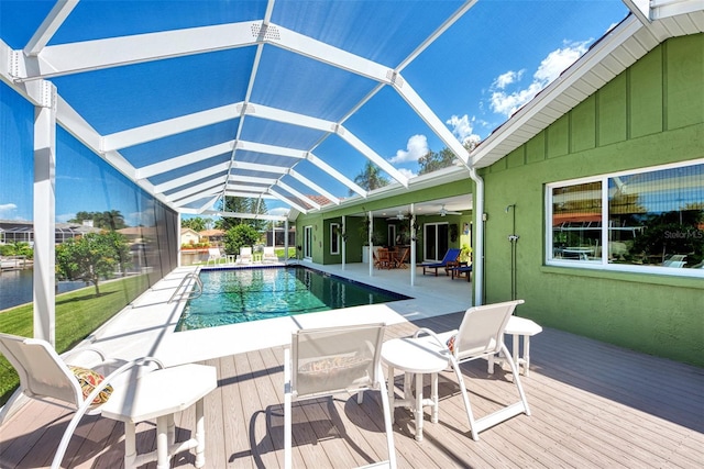 view of swimming pool featuring glass enclosure, a deck, and ceiling fan