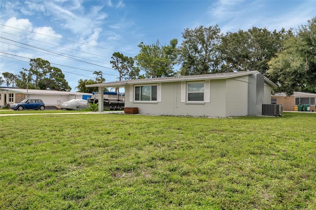 view of front of property with a front lawn, a carport, and central air condition unit