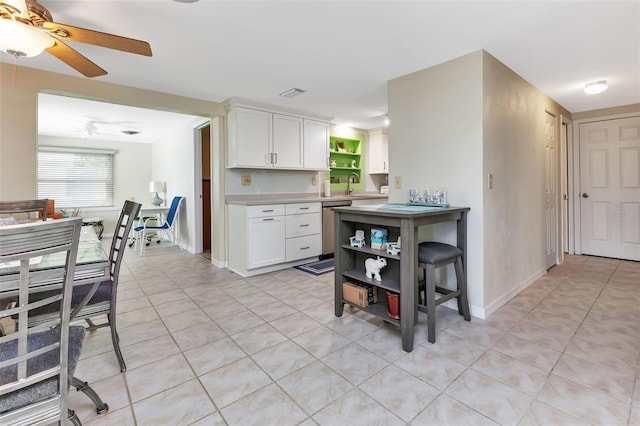 kitchen with stainless steel dishwasher, light tile patterned floors, and white cabinets