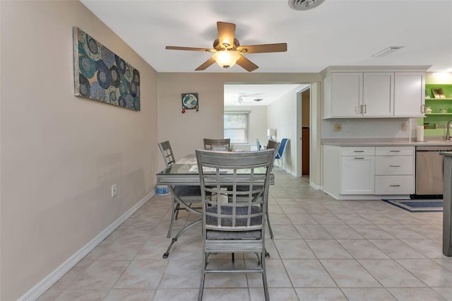 tiled dining area with ceiling fan and sink