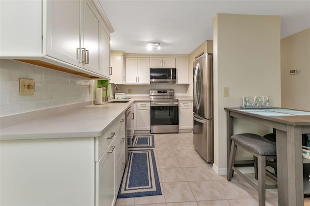 kitchen with light tile patterned flooring, a breakfast bar, sink, tasteful backsplash, and appliances with stainless steel finishes