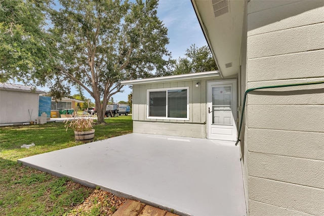 entrance to property featuring a patio and a lawn