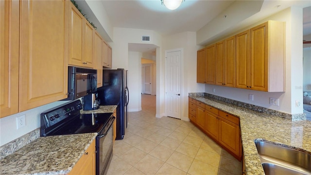 kitchen featuring light tile patterned flooring, sink, light stone counters, and black appliances