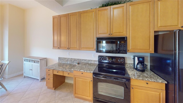 kitchen featuring black appliances, light stone countertops, light tile patterned floors, and built in desk