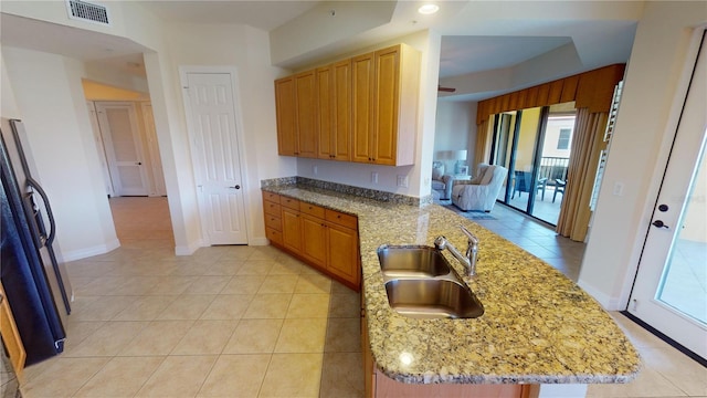 kitchen with sink, light stone countertops, light tile patterned floors, and refrigerator