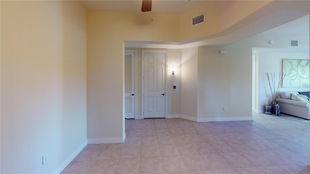 empty room with light tile patterned flooring, ceiling fan, and a towering ceiling