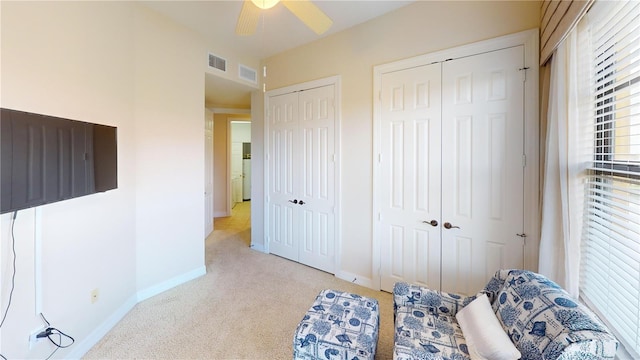 carpeted bedroom with multiple closets and ceiling fan