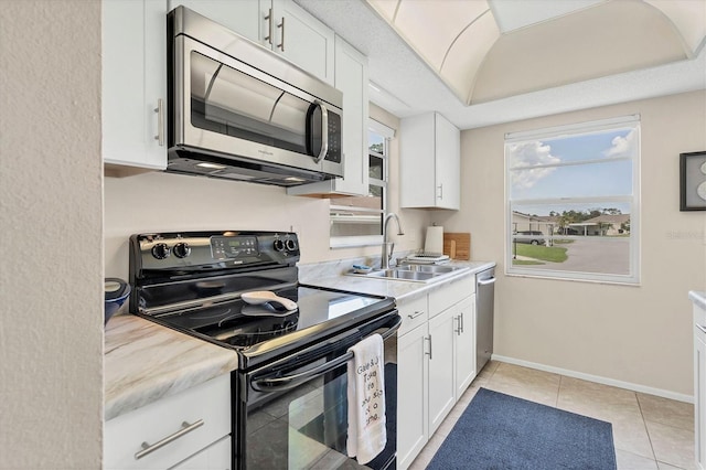 kitchen featuring appliances with stainless steel finishes, a raised ceiling, light tile patterned floors, and white cabinets