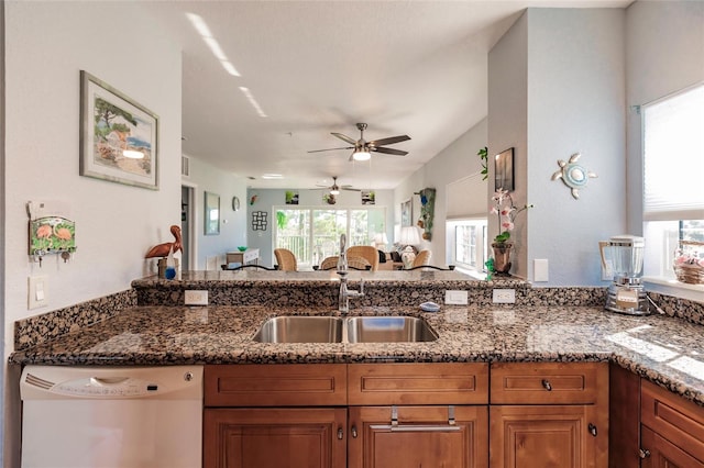 kitchen with dark stone counters, white dishwasher, ceiling fan, and sink