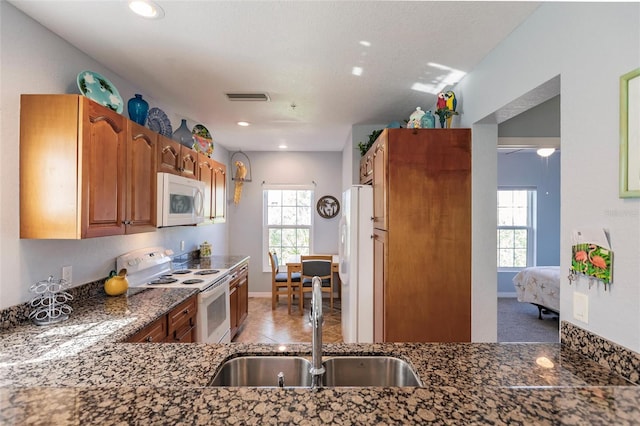 kitchen with sink, white appliances, and light colored carpet