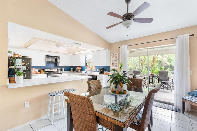 tiled dining room featuring vaulted ceiling, sink, and ceiling fan