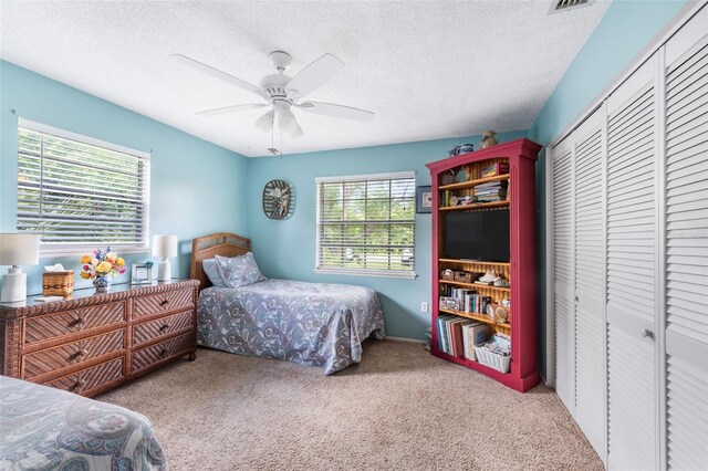 bedroom featuring a textured ceiling, light carpet, ceiling fan, and a closet