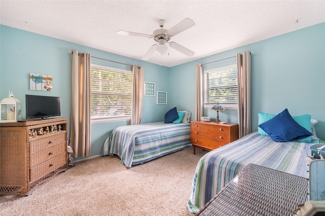 bedroom featuring multiple windows, light carpet, ceiling fan, and a textured ceiling