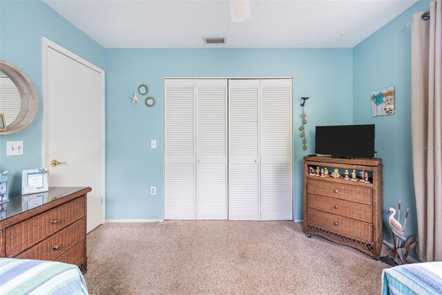 bedroom with a textured ceiling, carpet, a closet, and ceiling fan