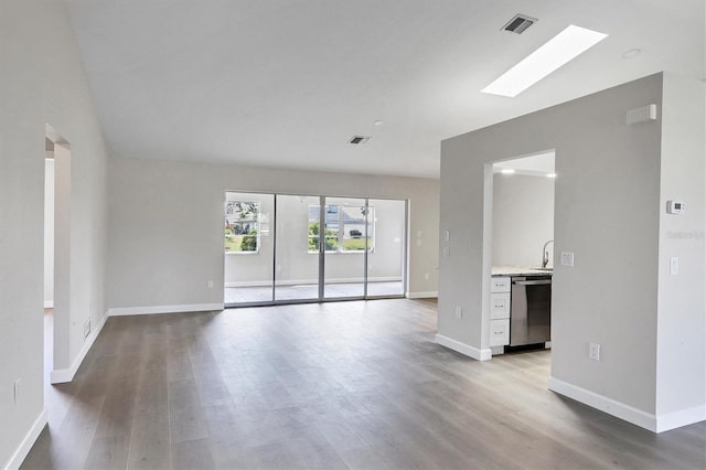 unfurnished room with baseboards, a skylight, visible vents, and light wood-style floors