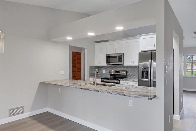 kitchen with visible vents, white cabinets, decorative backsplash, stainless steel appliances, and a sink