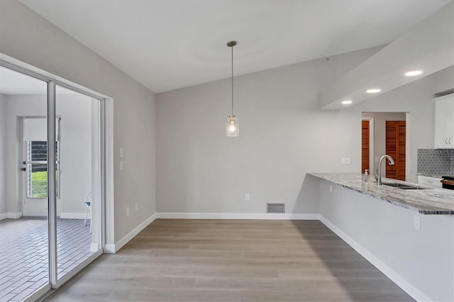 unfurnished dining area featuring visible vents, a sink, light wood-style flooring, and baseboards