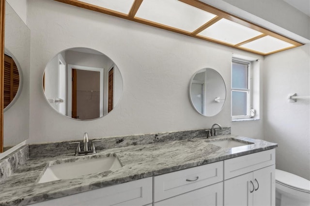 full bath featuring a sink, toilet, and double vanity