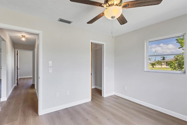 unfurnished bedroom featuring a closet, visible vents, light wood-style flooring, a spacious closet, and baseboards