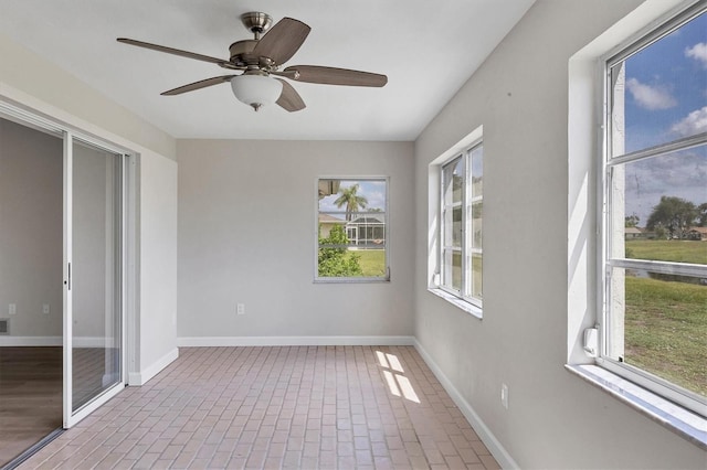 spare room with brick floor, baseboards, and a ceiling fan