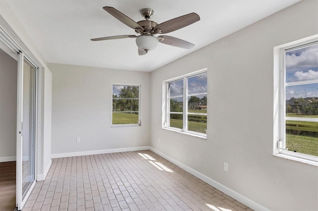 spare room with brick floor, ceiling fan, and baseboards