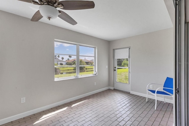 unfurnished room featuring ceiling fan, brick floor, and baseboards