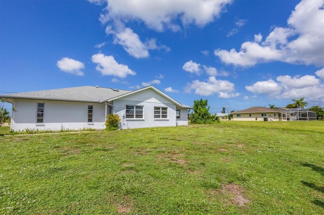 rear view of property with a lawn and stucco siding