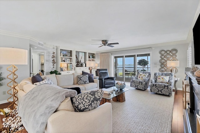 living area featuring ornamental molding, wood finished floors, visible vents, and baseboards