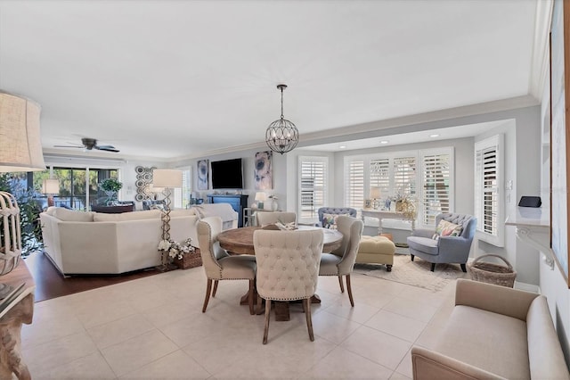 dining space with light tile patterned floors, crown molding, and ceiling fan with notable chandelier