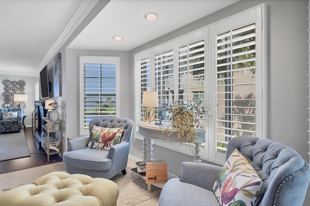 living area with a healthy amount of sunlight, crown molding, baseboards, and wood finished floors