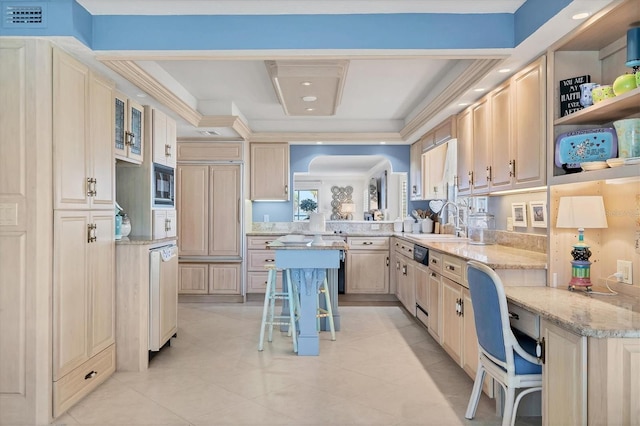 kitchen with light stone counters, a raised ceiling, glass insert cabinets, a sink, and black microwave