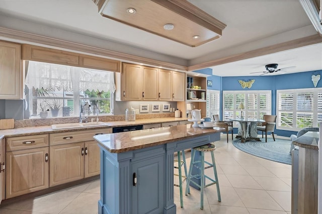 kitchen with light tile patterned flooring, a sink, a wealth of natural light, and a kitchen breakfast bar