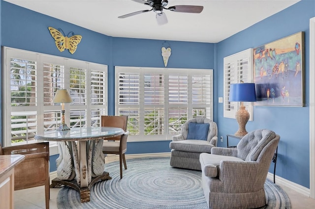 sitting room featuring ceiling fan, baseboards, and tile patterned floors