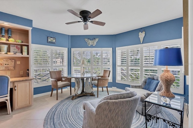 interior space featuring light tile patterned flooring, a ceiling fan, and baseboards