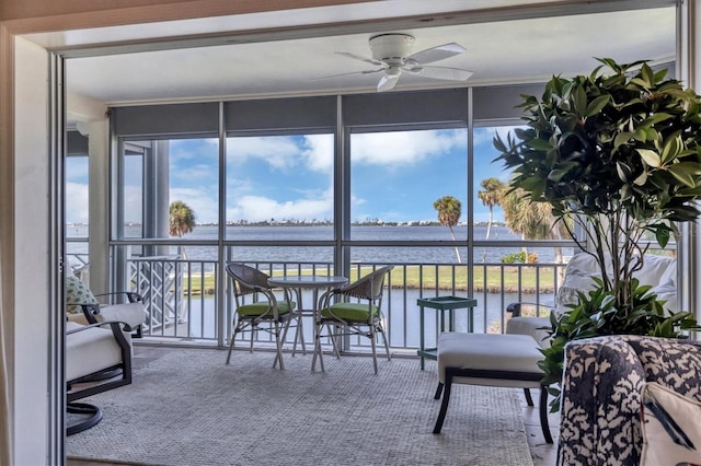 sunroom featuring a water view and a ceiling fan